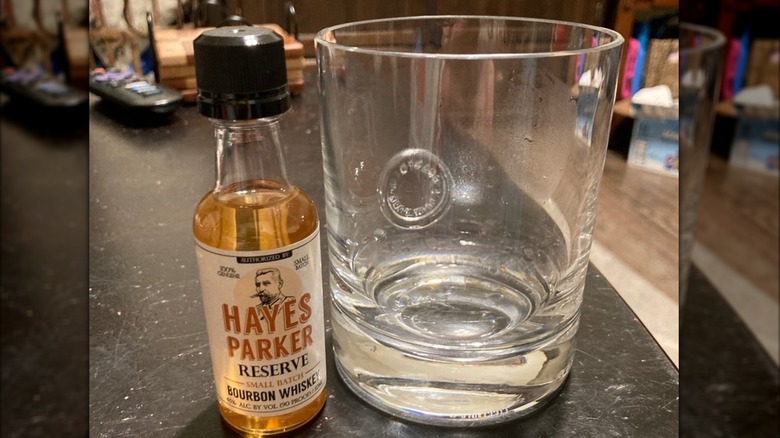 Small bottle of Hayes Parker next to a glass sitting on a black counter