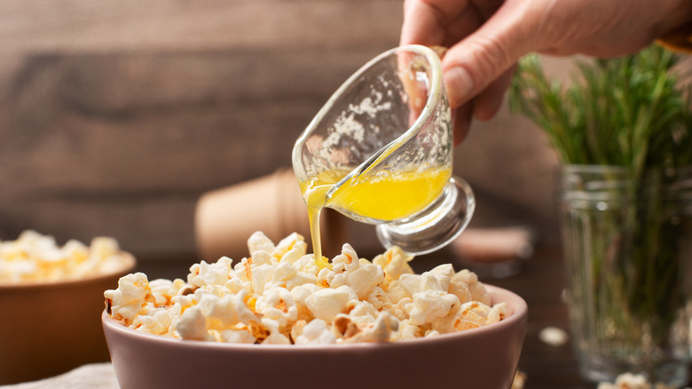 pouring melted butter on popcorn