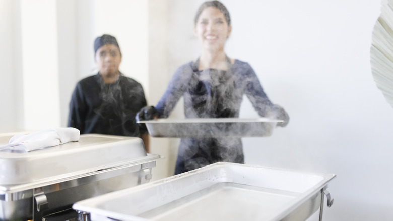 People refilling chafing dish at a buffet