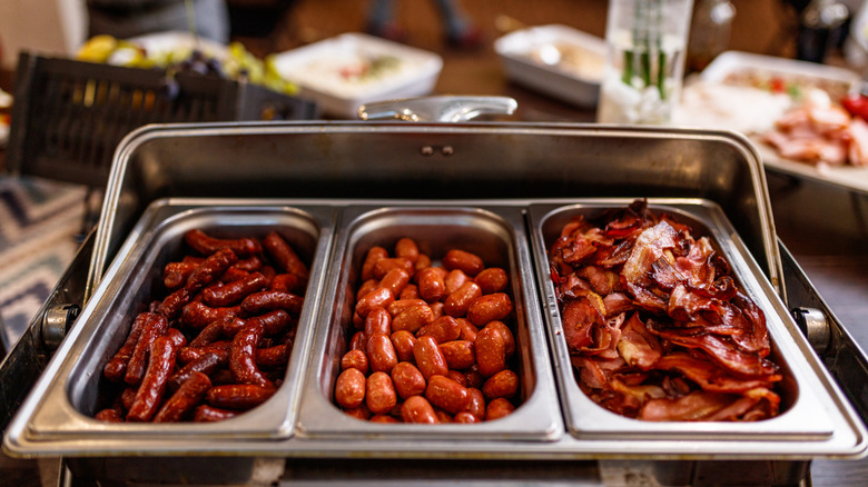 A tray with different breakfast meats at a buffet