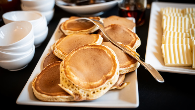 Pancakes tray at a buffet next to stacks of bowls