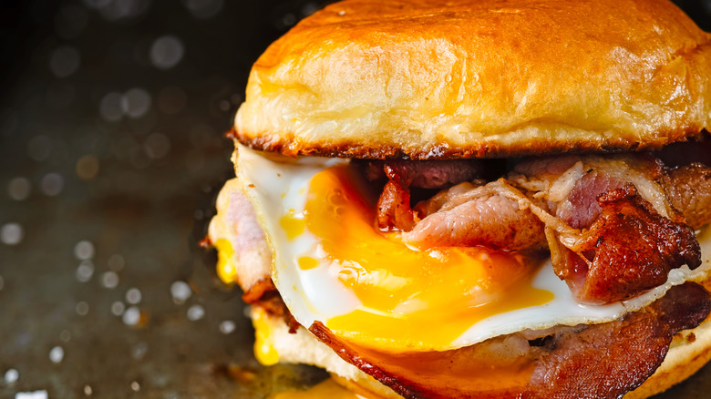 Close-up image of a bacon and egg sandwich with oozing yolk