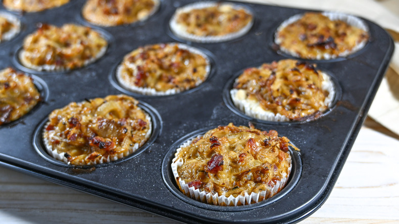 Baking tray placed on a wooden counter filled with baked savory muffins