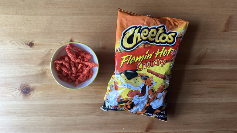 Flamin' Hot Crunchy Cheetos bag with bowl on wooden table