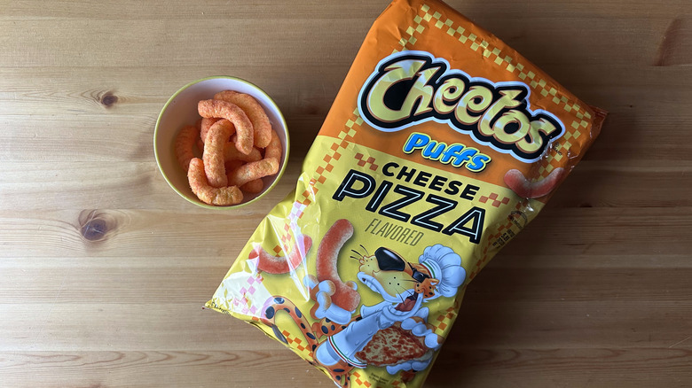 Puffs Cheese Pizza Cheetos bag with bowl on wooden table