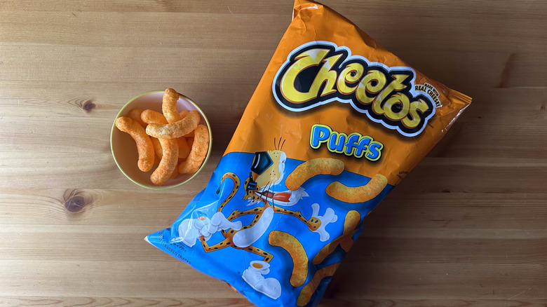Cheetos Puffs bag with bowl on wooden table