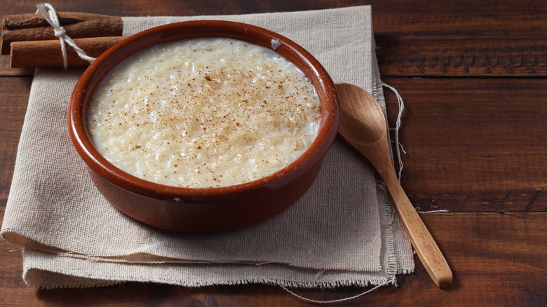 Bowl of rice pudding with wooden spoon and cinnamon sticks