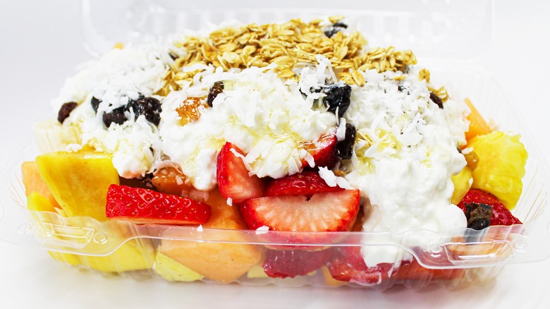 Takeout container filled with fruit, yogurt, and granola