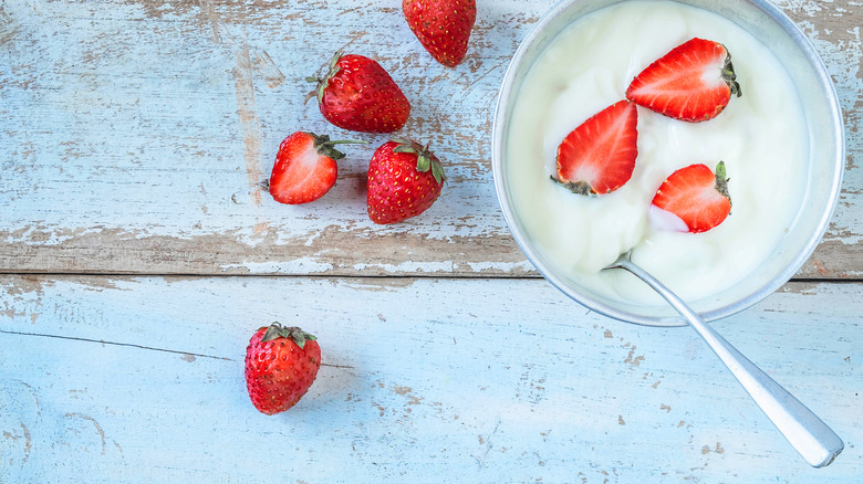 Bowl of strawberries and cream on wooden table