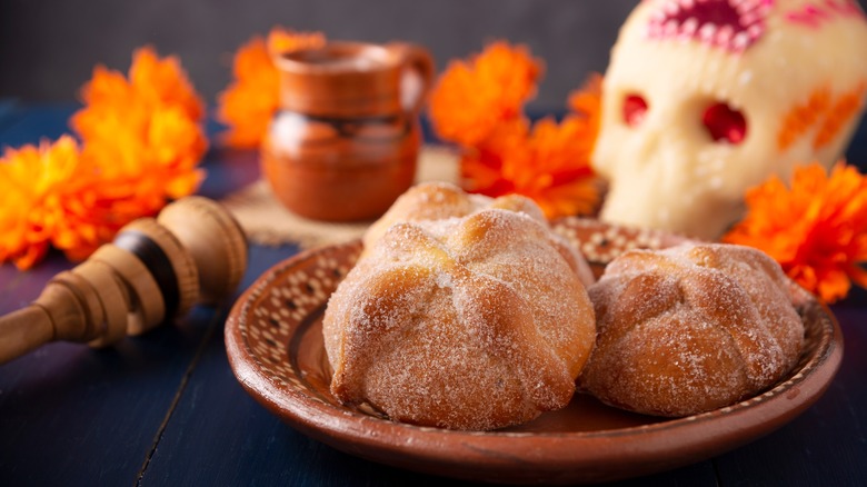 Pan de muertos on a brown plate with Day of the Dead decorations