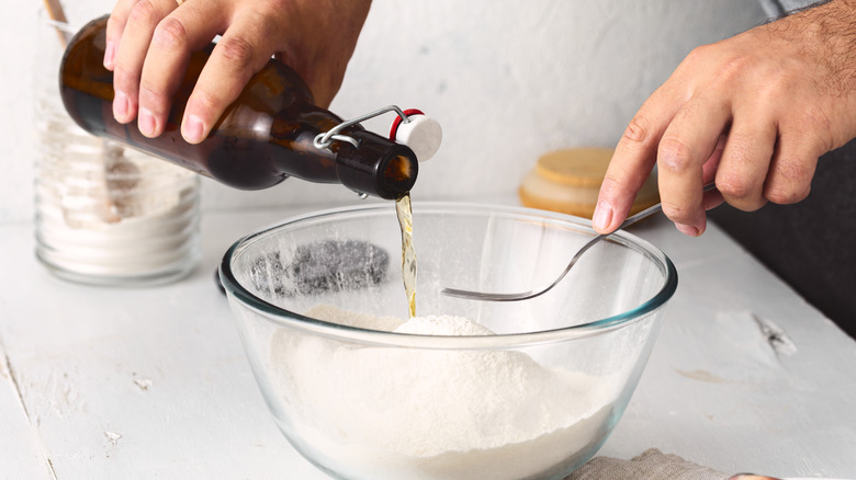 person pouring beer in bowl of flour