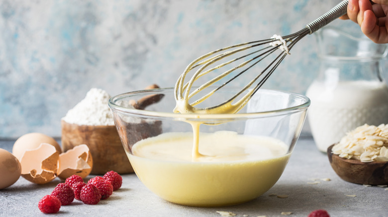 crepe batter dripping from whisk into bowl