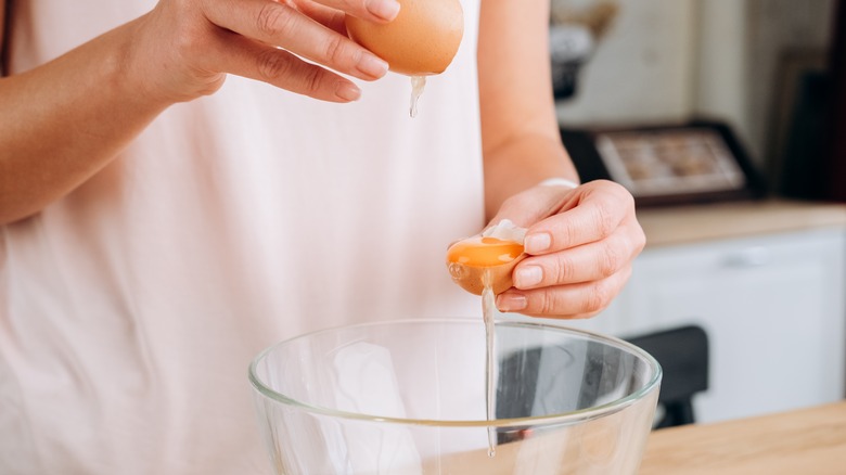 hand breaking egg into bowl 