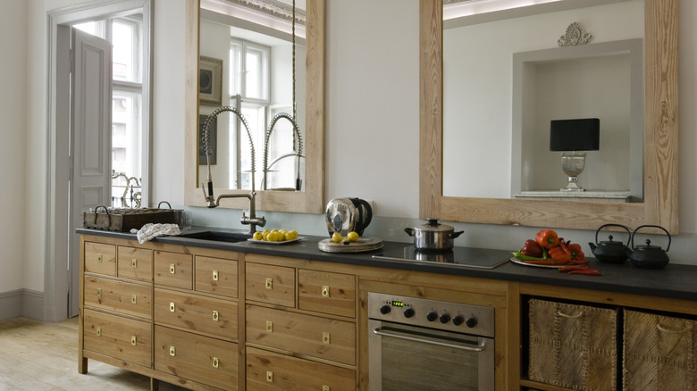 Wooden kitchen cabinets with stove and large mirrors