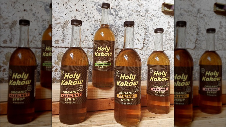 Holy Kakow coffee syrup bottles lined up on wooden shelves