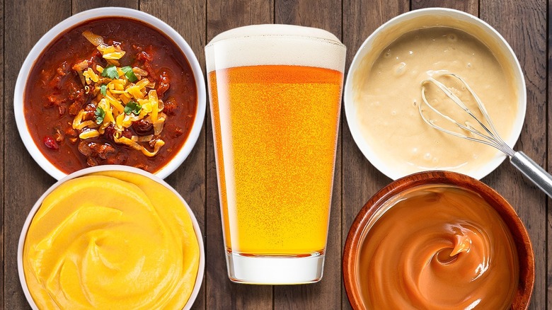 tall glass of beer surrounded by chili, batter, caramel sauce, and cheese sauce