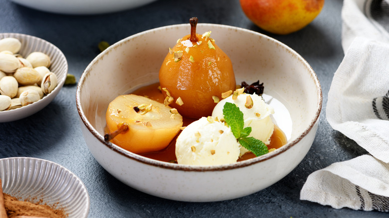 Poached pears in a white bowl with vanilla ice cream