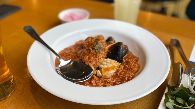 Grain dish with rich sauce in bowl with spoon