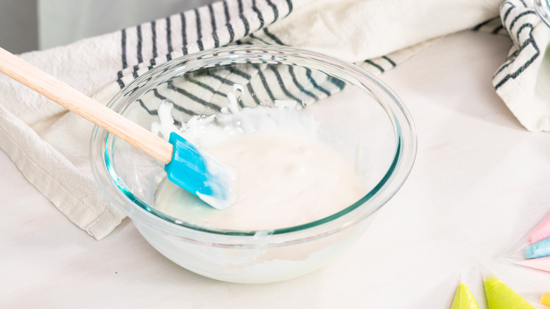 White royal icing in a glass bowl with a spatula