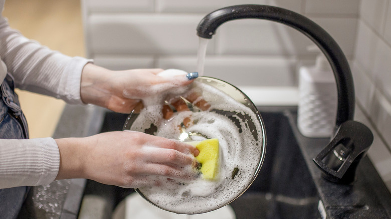 Person washing dishes in sink