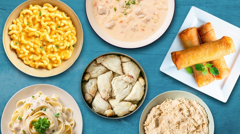 Canned crab meat surrounded by various dishes against a blue wooden tabletop background