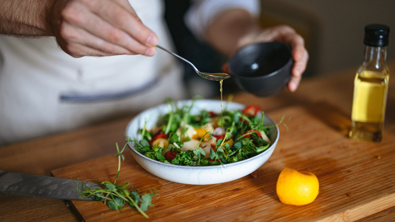 Person drizzling salad dressing