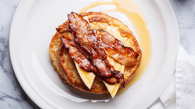 Caramelized pancakes topped with banana, bacon, and maple syrup