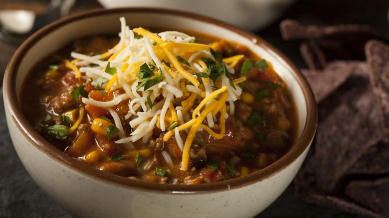 Bowl of chili with cheese and herbs on top
