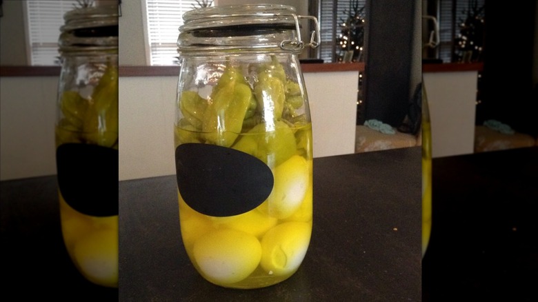 Eggs marinating in a jar of pepperoncini peppers on table