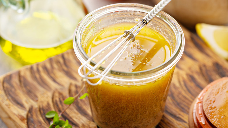 Homemade vinaigrette in glass jar with tiny whisk