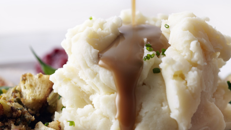 Thick gravy pouring over mashed potatoes