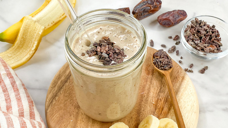 Date and banana smoothie in glass, topped with cacao nibs