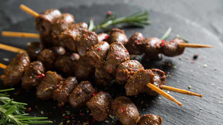 Skewers of seasoned chicken hearts on a platter