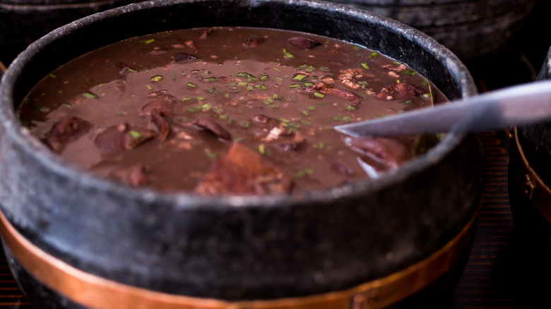 Crock of stewed black beans with a chive garnish