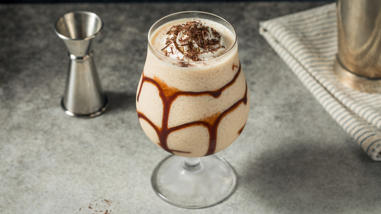Frozen mudslide with chocolate swirls and chocolate shavings next to a jigger