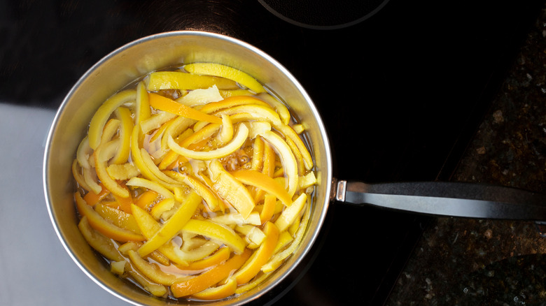 Candied orange peels in saucepan on black surface