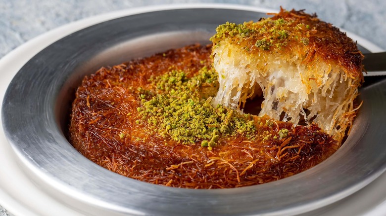 Knafeh slice with pistachios on silver plate