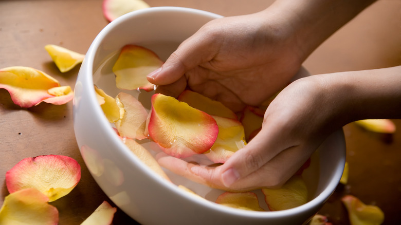 Person washing hands in a bowl of rose water