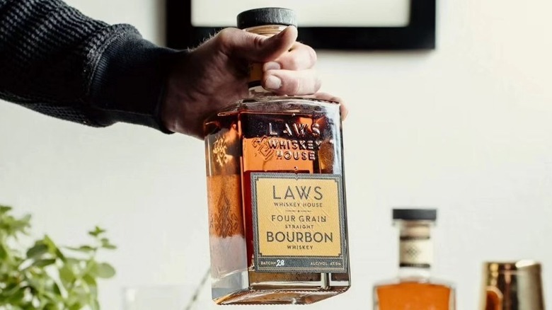 Hand holding a bottle of Laws bourbon