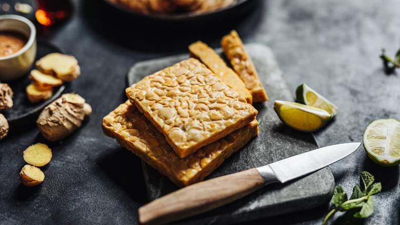 Preparing cooked tempeh on grey slab with knife