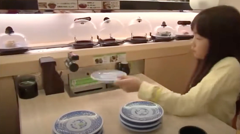 Woman inserting plates into automated dishwasher