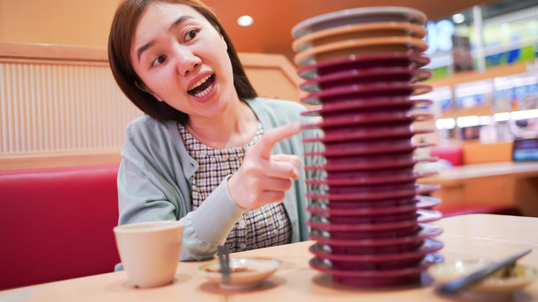 Woman counting number of color coded sushi plates