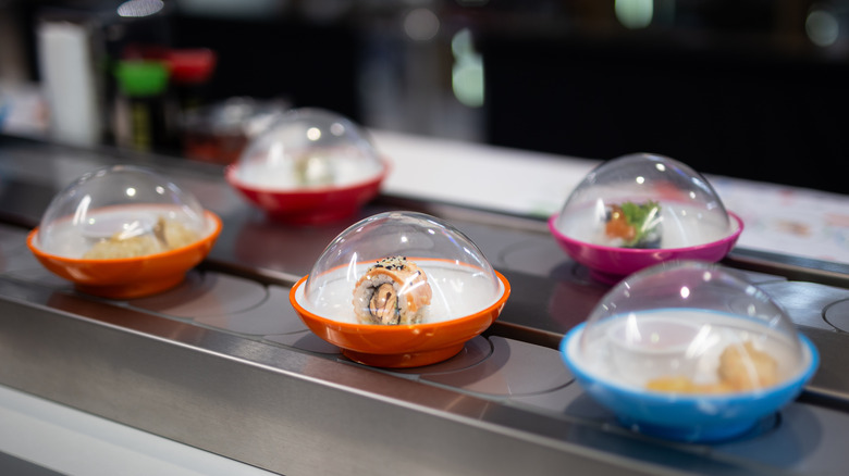 Covered plates of sushi on a conveyor