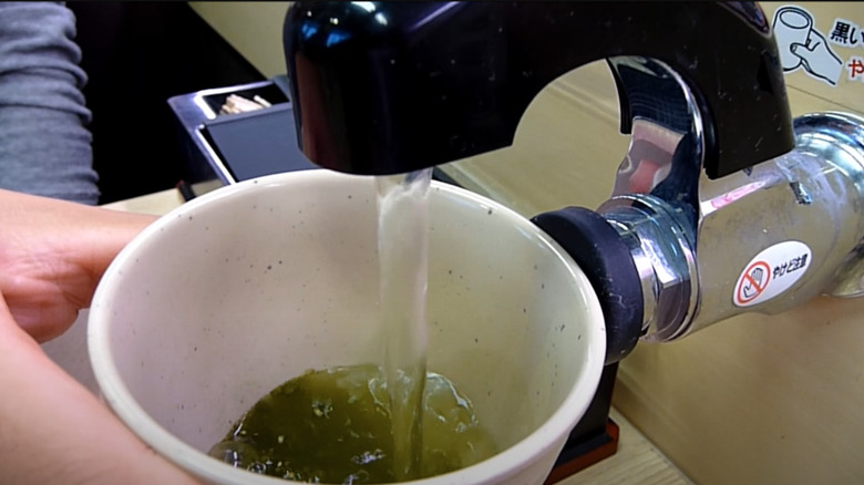 Person using automatic green tea dispenser