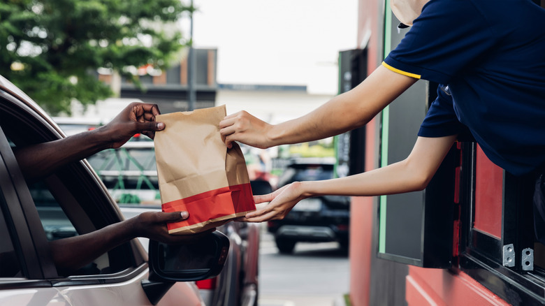 McDonald's employee handing customer food in drive-thru window