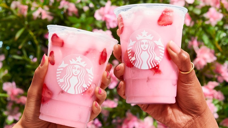 hands holding pink drink