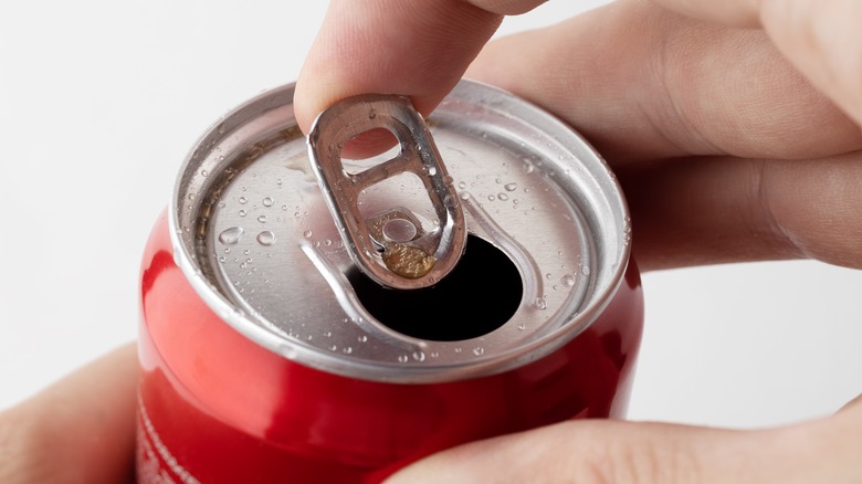 Open can of Coke in hand