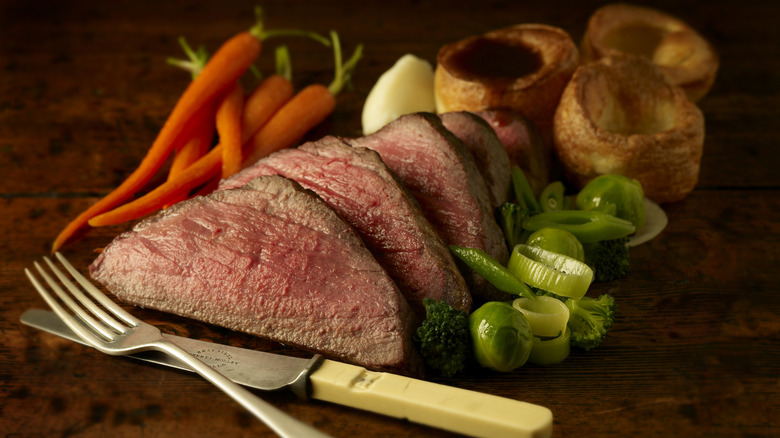 roast beef on table with garnishes and utensils