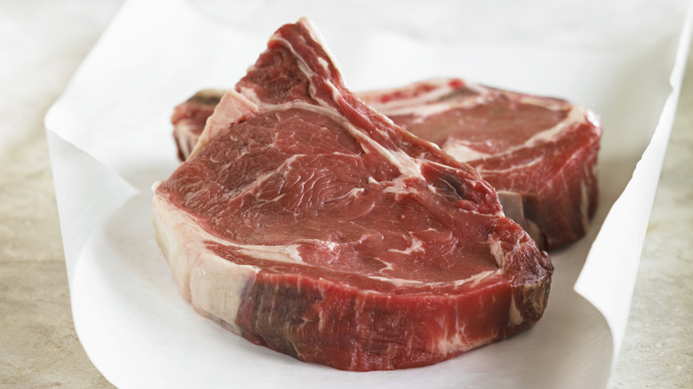 Two beef steaks on piece of white parchment paper