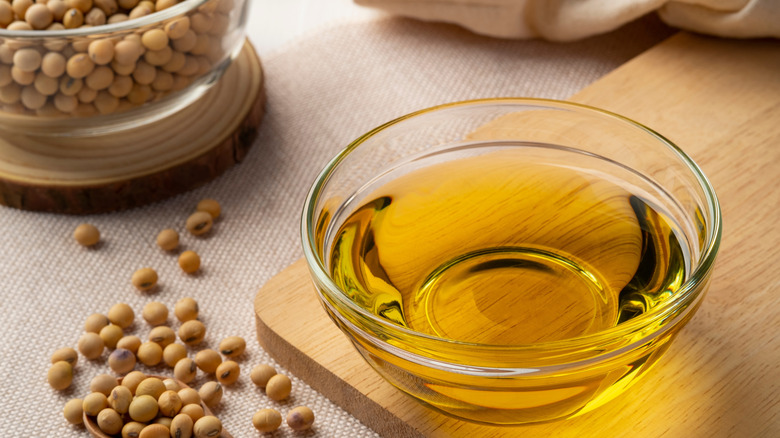 Bowl of soybean oil next to dried soy beans